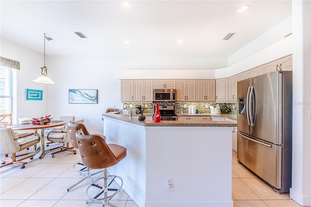 kitchen with a breakfast bar, tasteful backsplash, light tile patterned floors, pendant lighting, and stainless steel appliances