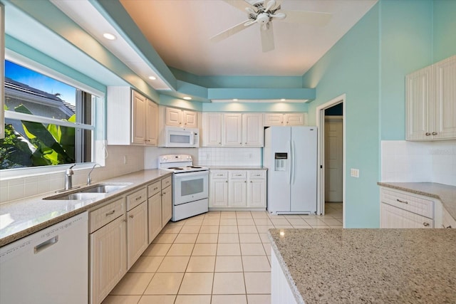 kitchen with white appliances, light stone countertops, backsplash, ceiling fan, and sink