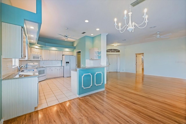 kitchen featuring white appliances, light hardwood / wood-style floors, white cabinetry, backsplash, and ceiling fan with notable chandelier