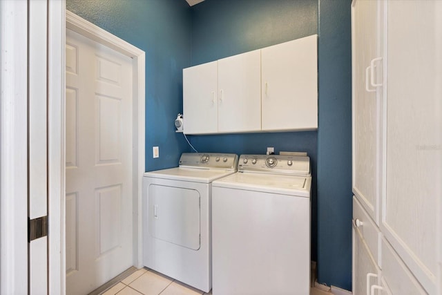 laundry room featuring cabinets, washing machine and dryer, and light tile patterned floors