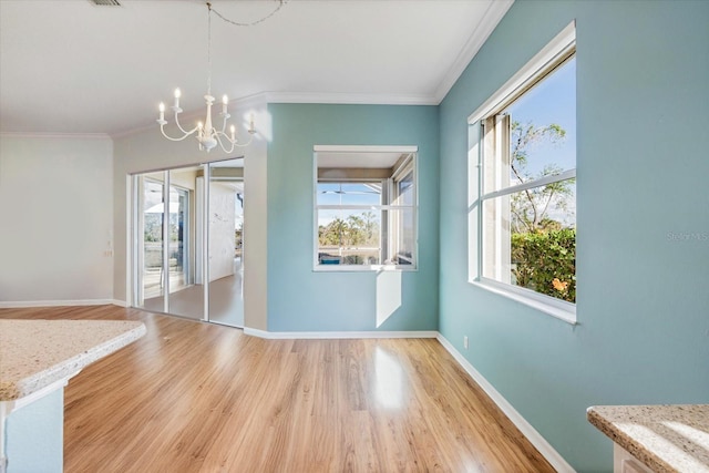 unfurnished dining area with ornamental molding, a notable chandelier, and light hardwood / wood-style flooring