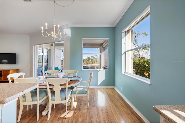 dining room with a notable chandelier, light hardwood / wood-style flooring, and crown molding