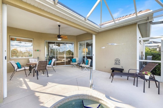 view of patio with ceiling fan and glass enclosure