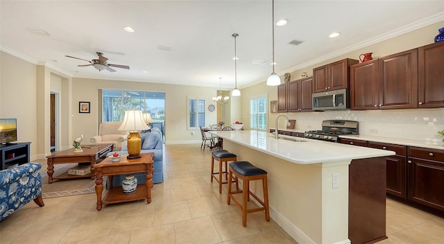 kitchen featuring sink, an island with sink, decorative light fixtures, a kitchen bar, and stainless steel appliances