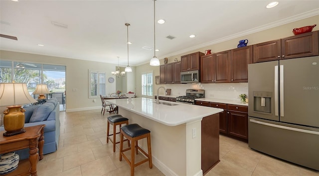 kitchen with pendant lighting, a kitchen island with sink, a kitchen breakfast bar, sink, and stainless steel appliances