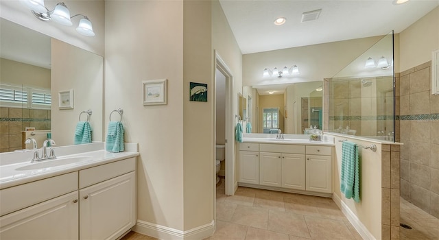 bathroom featuring a tile shower, a healthy amount of sunlight, tile patterned flooring, toilet, and vanity