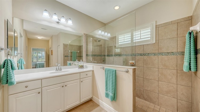 bathroom with tile patterned flooring, vanity, and tiled shower