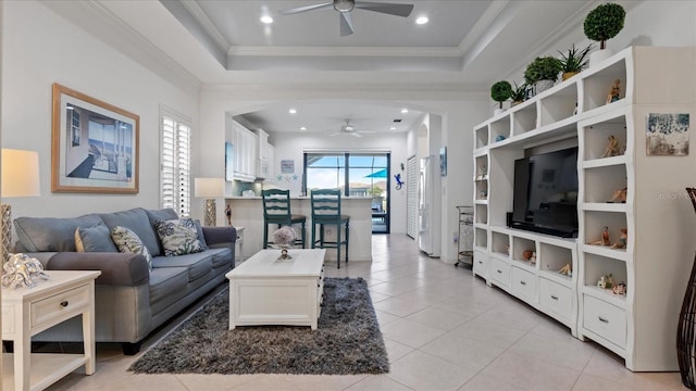 tiled living room featuring a tray ceiling, ceiling fan, and crown molding