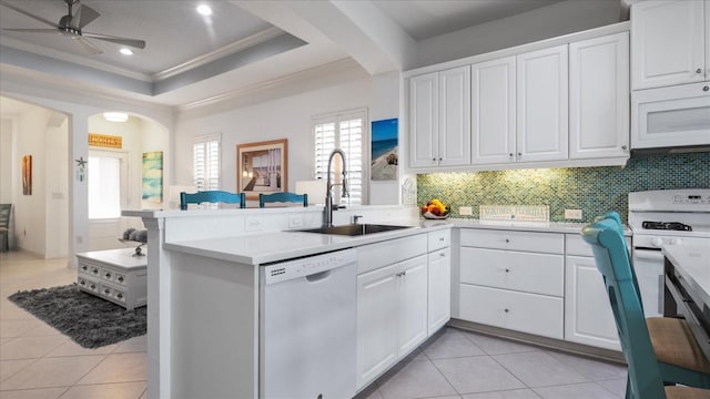 kitchen featuring kitchen peninsula, sink, white cabinets, and white appliances