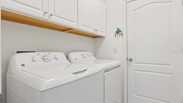 clothes washing area featuring washer and dryer and cabinets