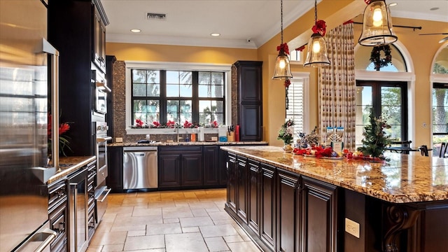 kitchen featuring appliances with stainless steel finishes, dark brown cabinetry, a kitchen island, and hanging light fixtures