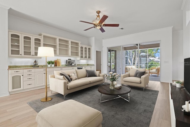 living room featuring light hardwood / wood-style floors, ceiling fan, and crown molding