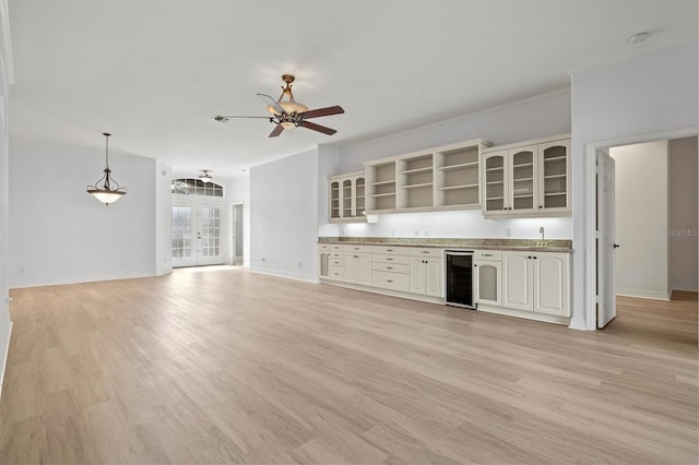 kitchen featuring pendant lighting, ornamental molding, wine cooler, and light hardwood / wood-style flooring