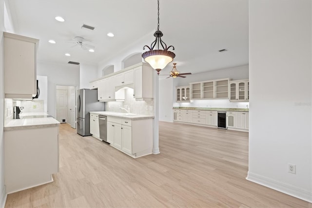 kitchen featuring stainless steel appliances, backsplash, light hardwood / wood-style floors, decorative light fixtures, and white cabinets