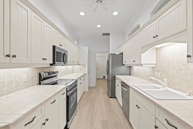 kitchen with white cabinetry, sink, stainless steel appliances, and light hardwood / wood-style floors