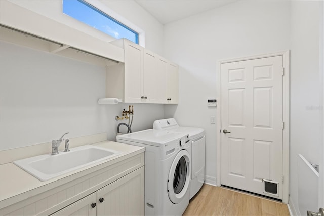 washroom with light hardwood / wood-style floors, sink, cabinets, and independent washer and dryer