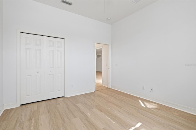 unfurnished bedroom featuring a high ceiling, light hardwood / wood-style flooring, and a closet