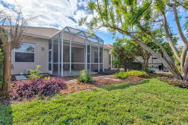 rear view of property featuring a lanai and a lawn