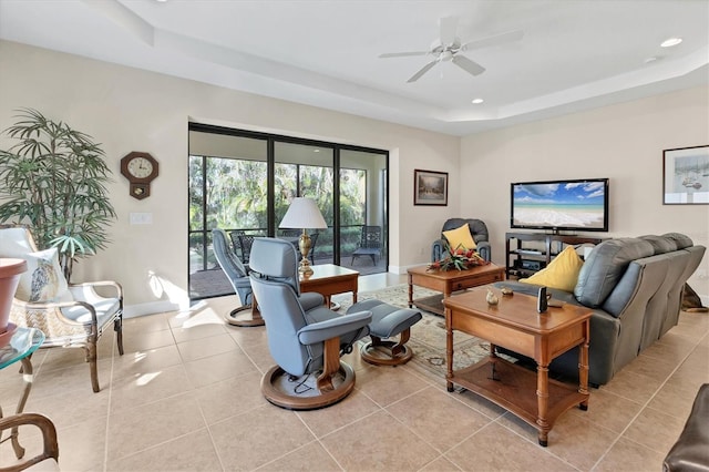 tiled living room featuring ceiling fan and a raised ceiling