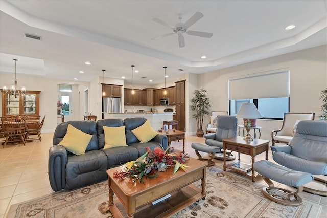 tiled living room with a tray ceiling and ceiling fan with notable chandelier