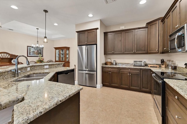 kitchen featuring light stone countertops, dark brown cabinetry, stainless steel appliances, sink, and pendant lighting