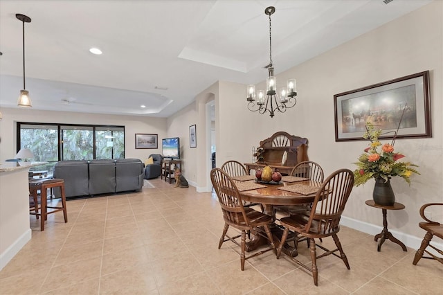 tiled dining space with a tray ceiling and a notable chandelier