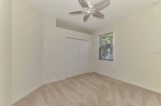 unfurnished bedroom featuring ceiling fan, a closet, and light colored carpet