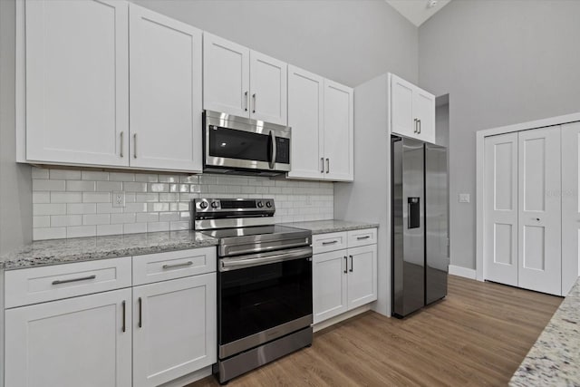 kitchen with white cabinetry, stainless steel appliances, and light hardwood / wood-style flooring