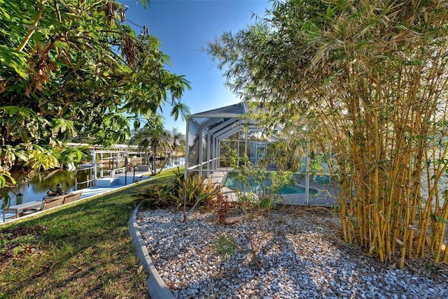 view of yard featuring a boat dock, a water view, and glass enclosure