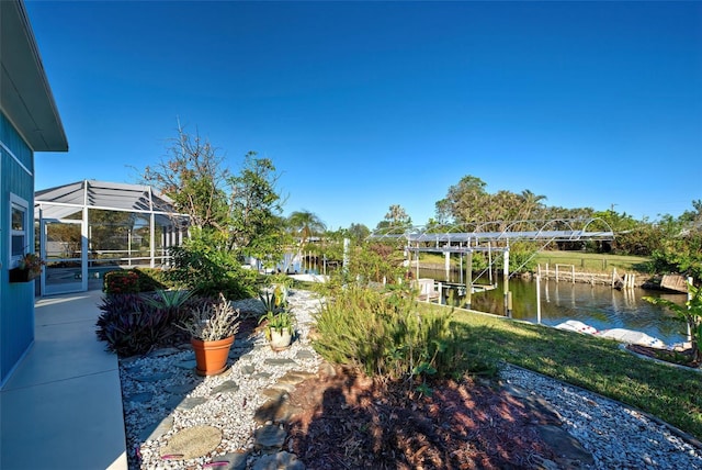 view of yard featuring glass enclosure, a dock, and a water view