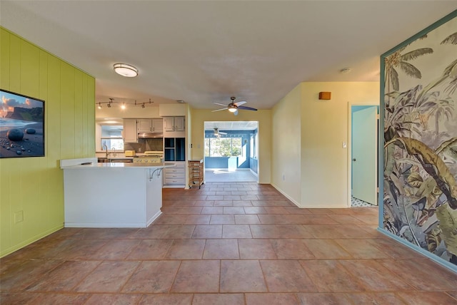 kitchen featuring stove, backsplash, white cabinets, ceiling fan, and kitchen peninsula