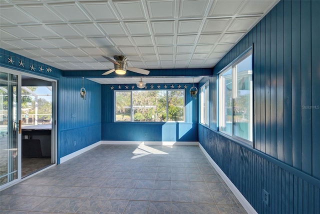 unfurnished sunroom featuring ceiling fan and plenty of natural light