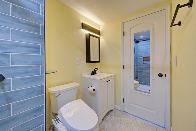 bathroom featuring a textured ceiling, vanity, and toilet