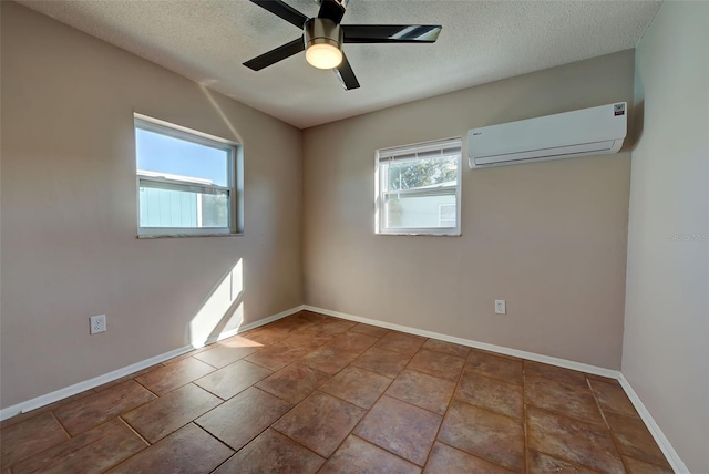 spare room with a wall unit AC, ceiling fan, light tile patterned floors, and a textured ceiling