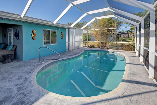 view of pool with glass enclosure and a patio area