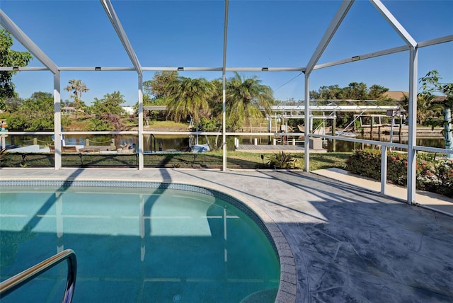 view of pool with glass enclosure, a patio area, and a water view