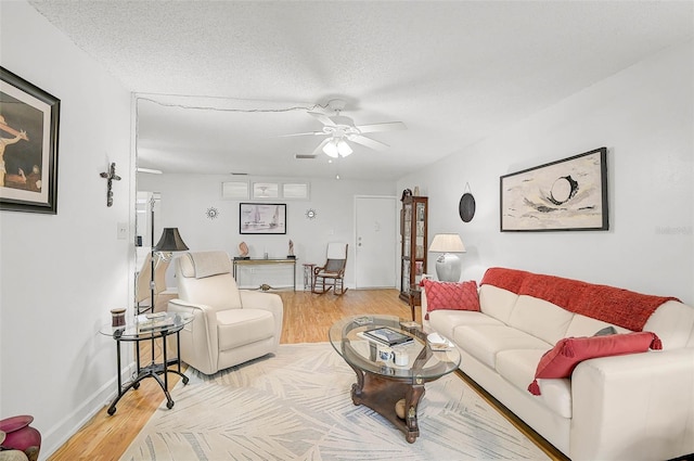 living room featuring ceiling fan, wood-type flooring, and a textured ceiling