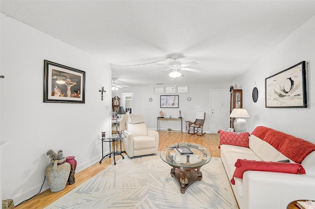 living room with ceiling fan, wood-type flooring, and a textured ceiling