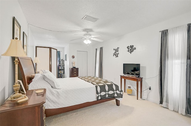 carpeted bedroom with ceiling fan and a textured ceiling