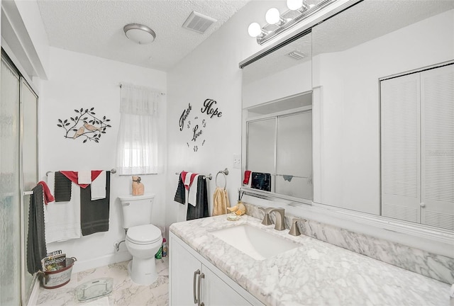 bathroom with vanity, a textured ceiling, toilet, and a shower with shower door