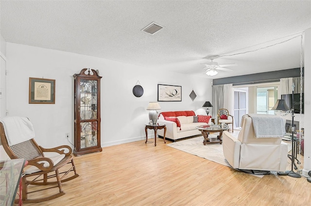 living room featuring ceiling fan, a textured ceiling, and light hardwood / wood-style flooring