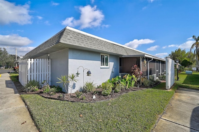 view of side of home featuring a sunroom and a yard