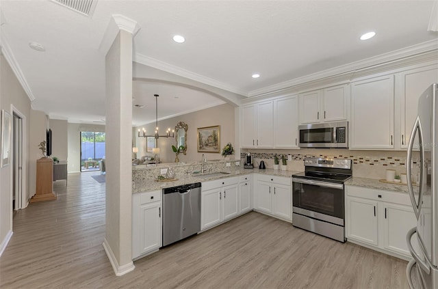 kitchen featuring decorative backsplash, kitchen peninsula, stainless steel appliances, white cabinets, and hanging light fixtures