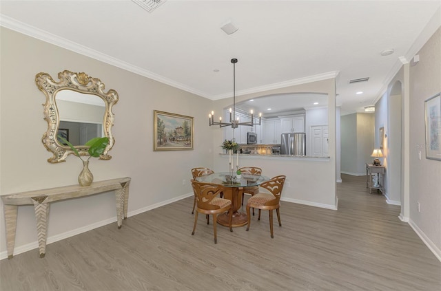 dining space with an inviting chandelier, light hardwood / wood-style flooring, and ornamental molding