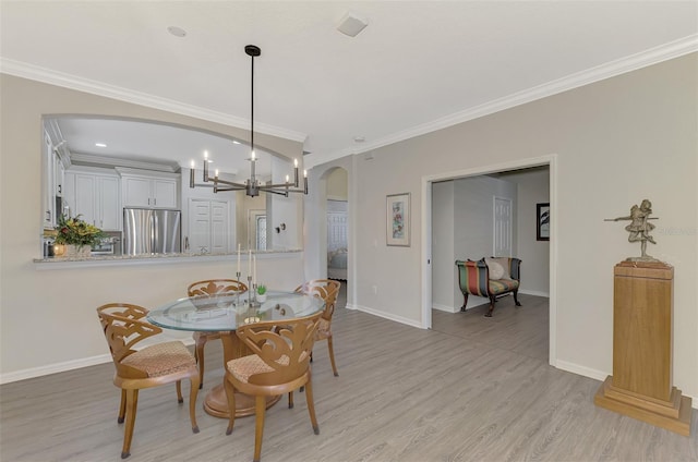 dining area featuring light hardwood / wood-style floors, an inviting chandelier, and crown molding