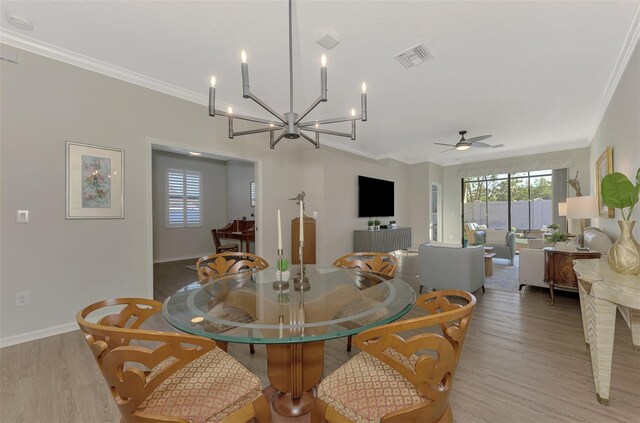 dining area featuring ceiling fan with notable chandelier, wood-type flooring, and crown molding