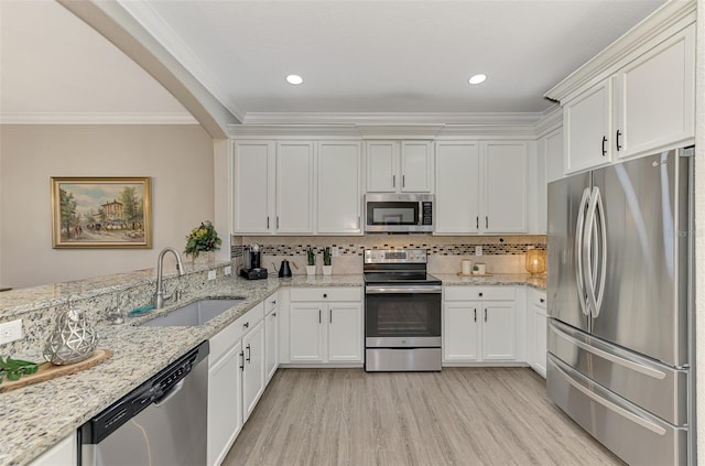 kitchen featuring light stone countertops, white cabinetry, sink, stainless steel appliances, and tasteful backsplash