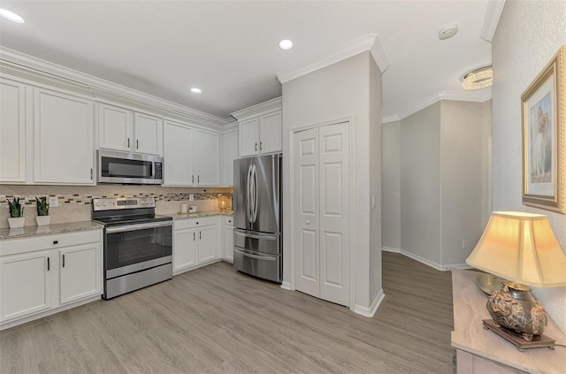 kitchen with white cabinets, decorative backsplash, stainless steel appliances, and crown molding