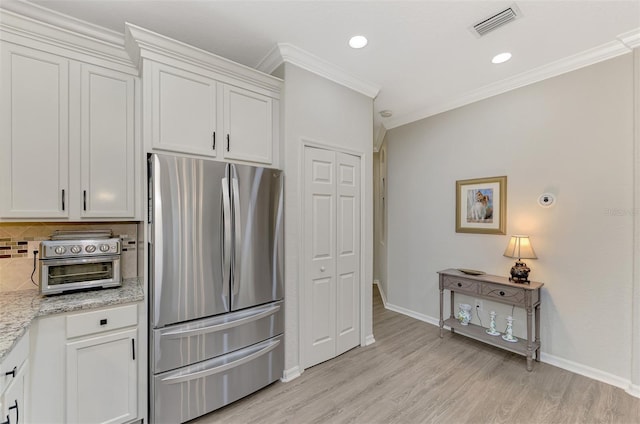 kitchen featuring backsplash, stainless steel fridge, and white cabinets