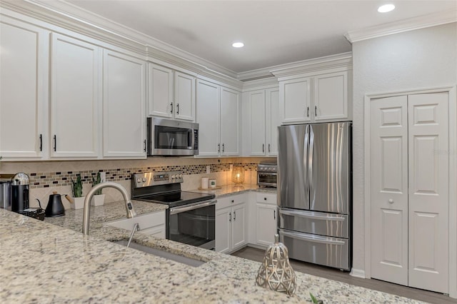 kitchen with tasteful backsplash, white cabinetry, stainless steel appliances, and light stone counters